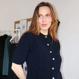 pige i strikket blå cardigan med korte ærmer og hvide knapper