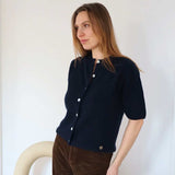 pige i strikket blå cardigan med korte ærmer og hvide knapper